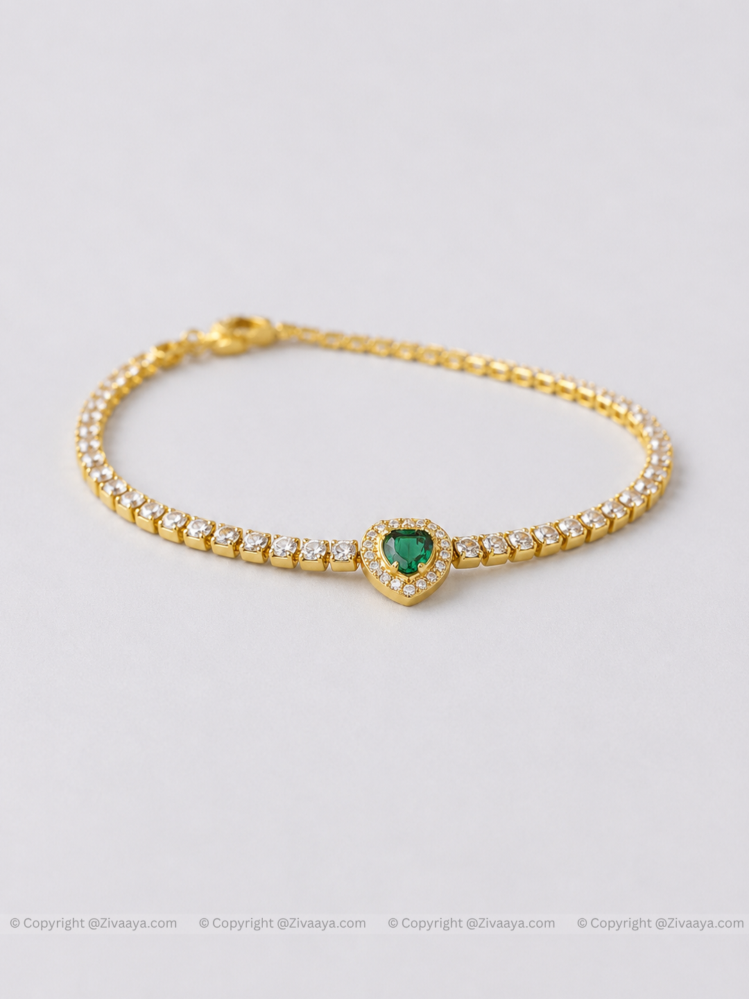 Gold bracelet with a heart-shaped green gemstone on a light gray background