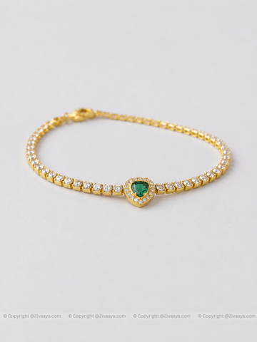 Gold bracelet with a heart-shaped green gemstone on a light gray background